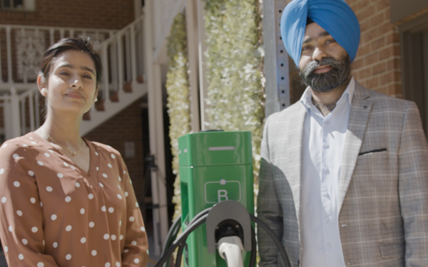 Two people standing in front of EV charger