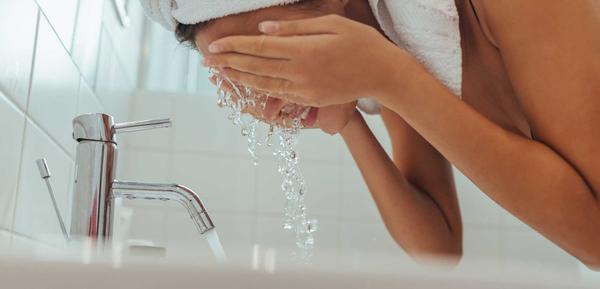 Woman washing her face with hot water