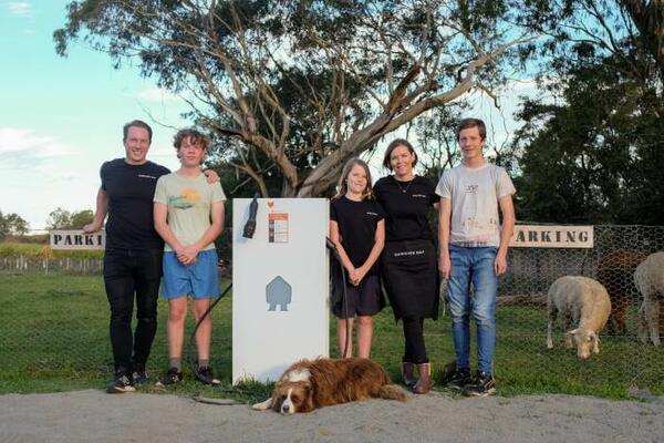  Mike and Katrina from Dawning Day Farms standing near new EV charger, with family and sheep