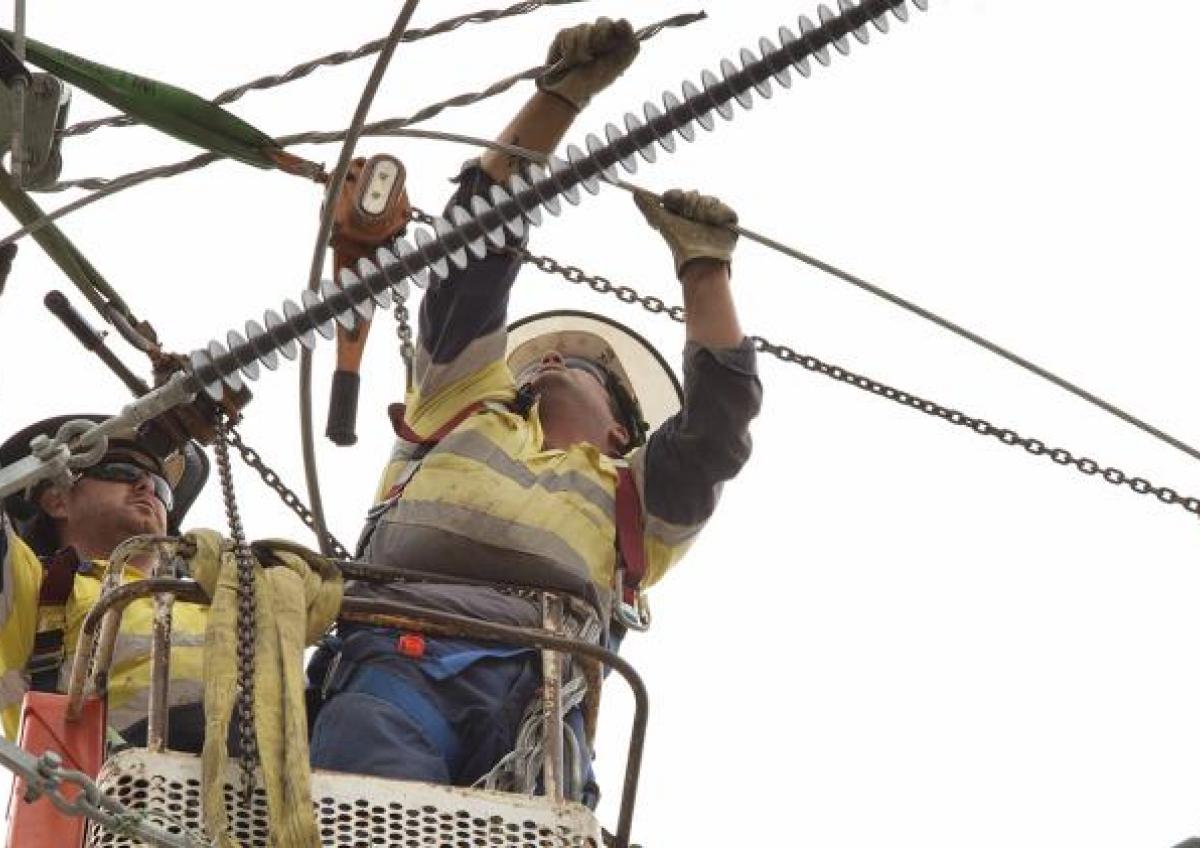 Industry workers with wires on electricity pole