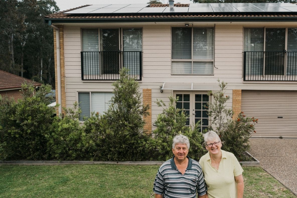 Man and woman look outside their home which has solar panels