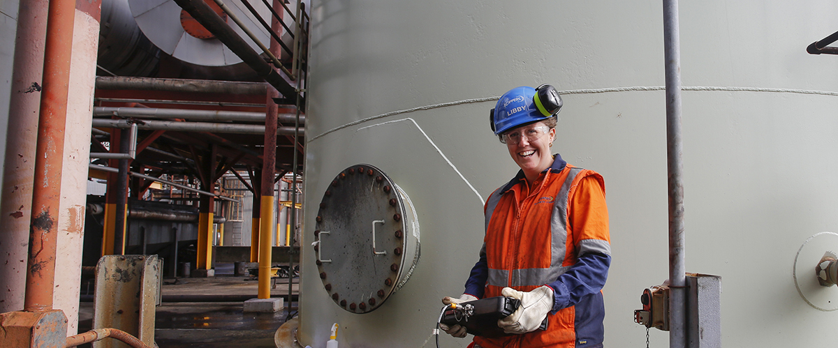 Woman holding gas meter wearing hard hat