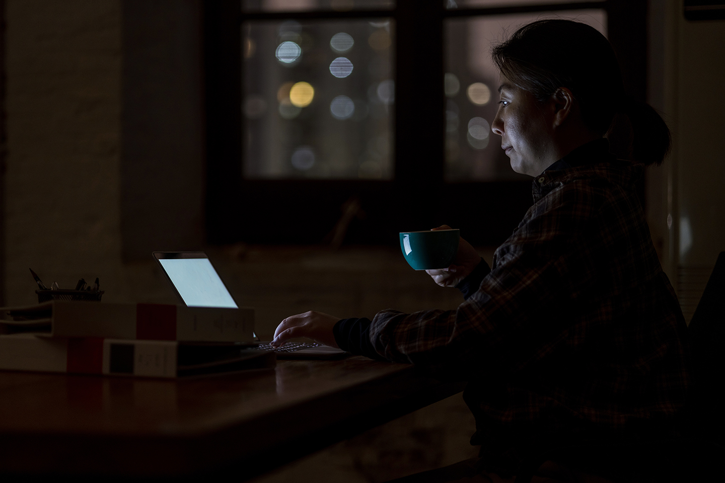 Woman sitting in the dark looking at a laptop screen