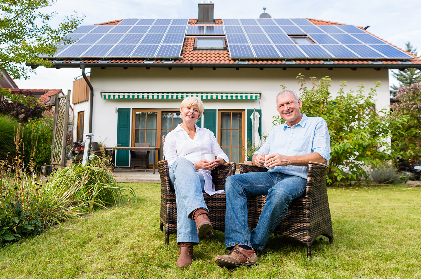 Two people sitting outside house with solar panels