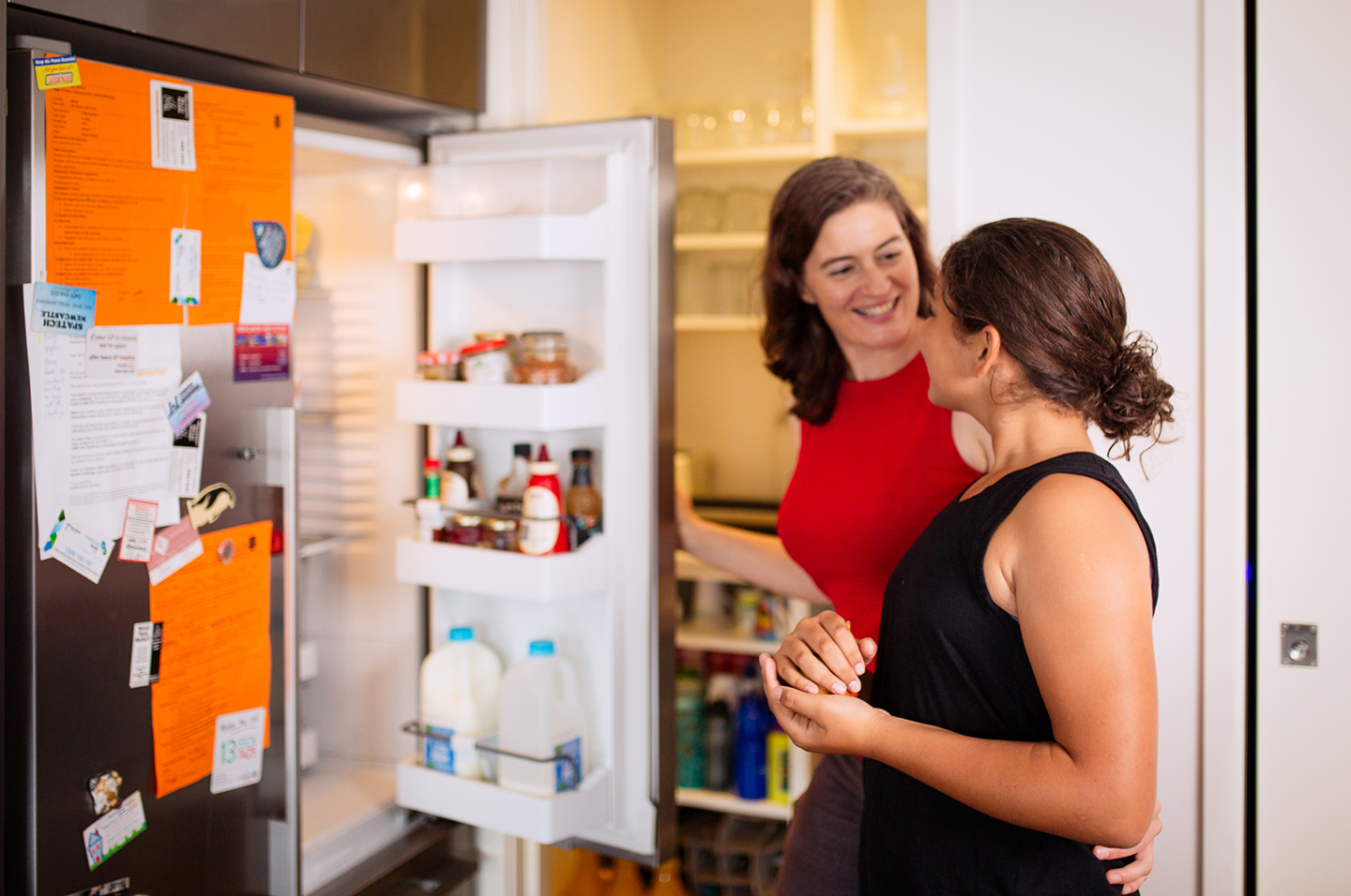 Parent and child in kitchen with open fridge