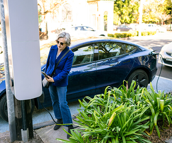Person charging electric vehicle at outdoor charger