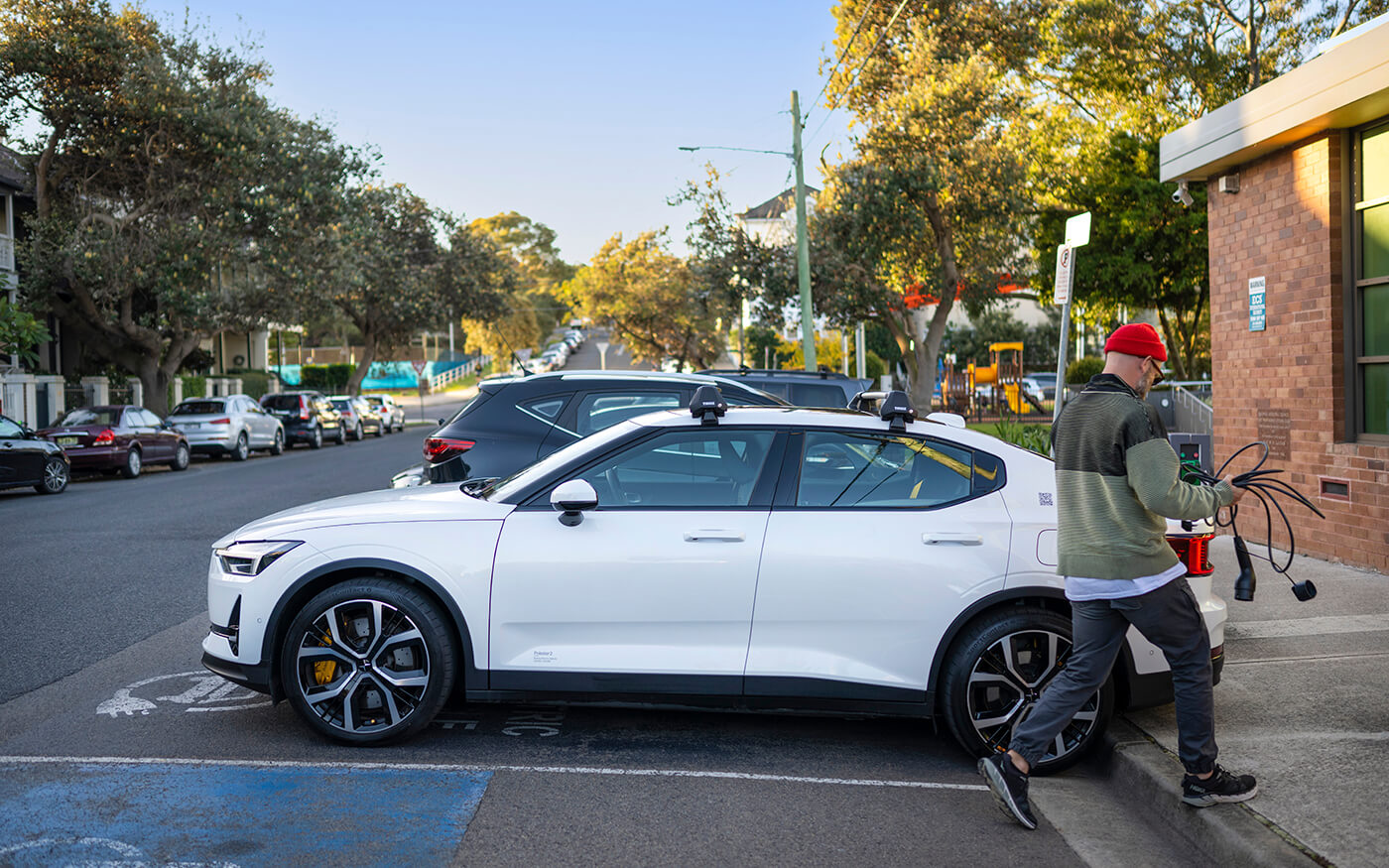 Person using kerbside electric vehicle charger, holding charging cable