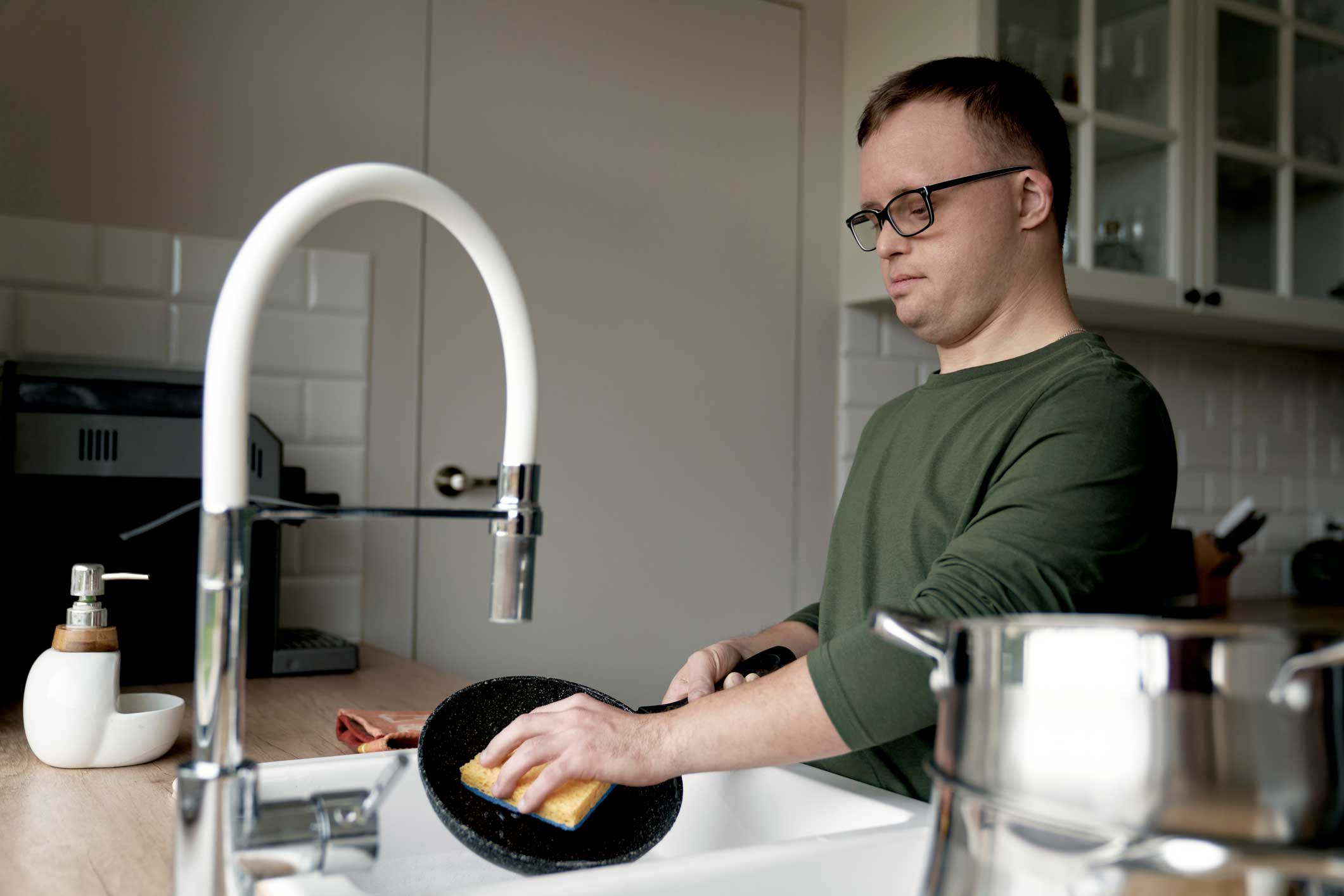 Man washing dishes with hot water in sink