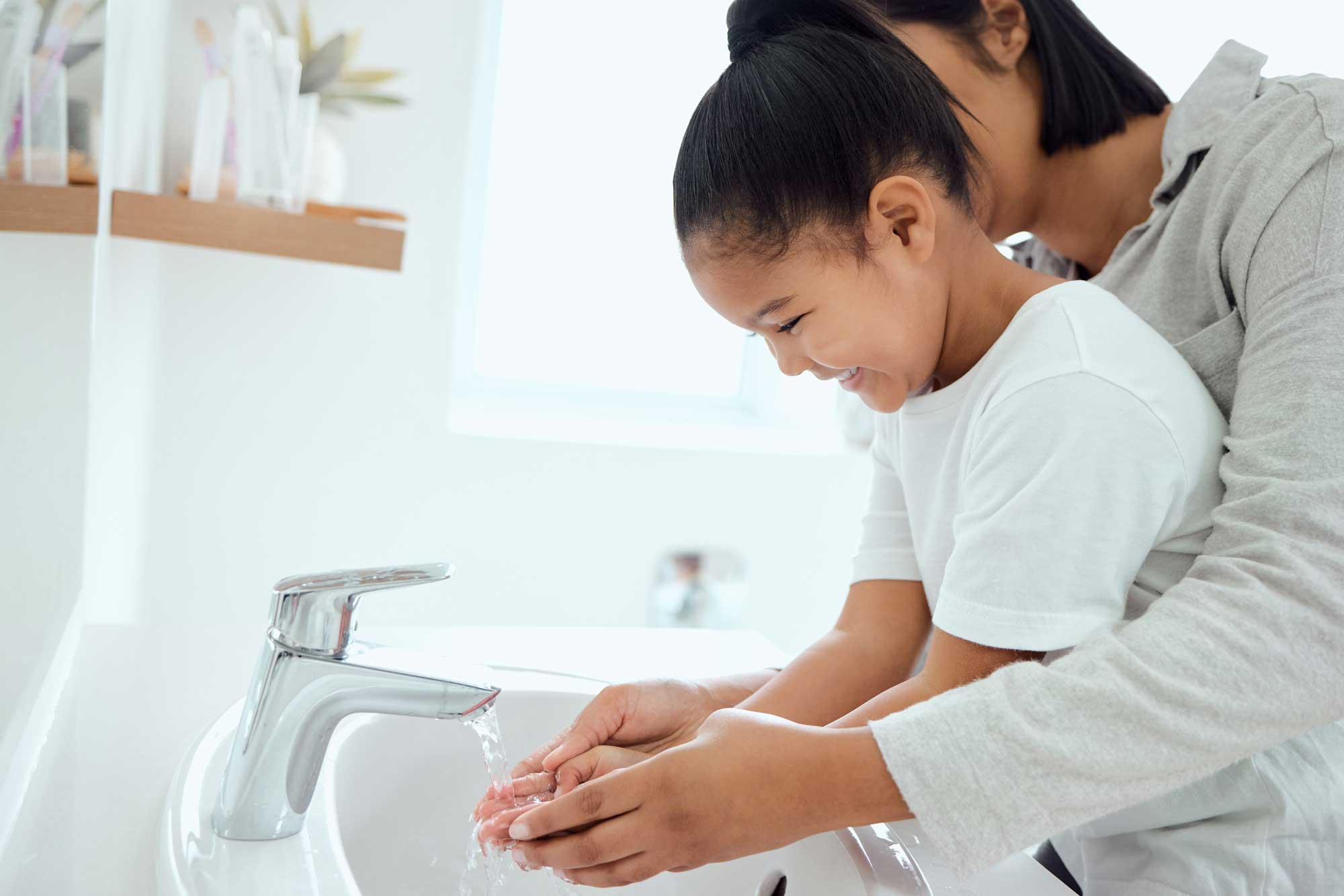 Parent washing child's hands in warm water