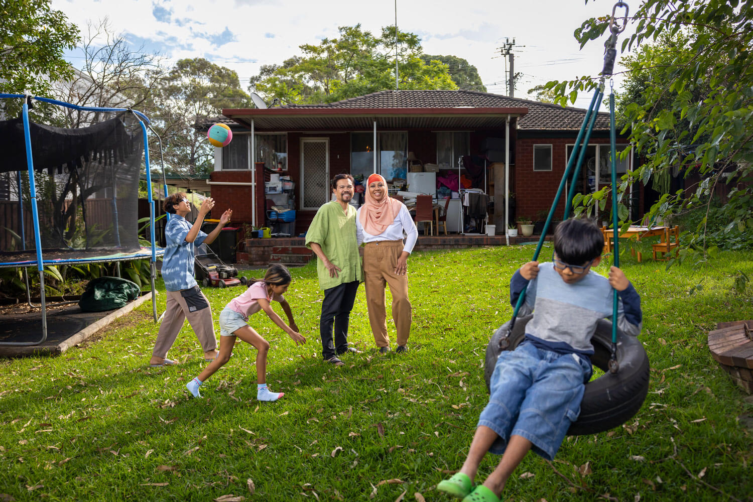 Family standing in their home's backyard surrounded by their children