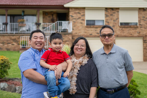 Smiling family standing in front of home