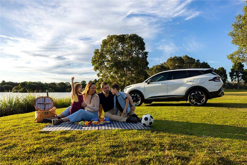 Image of family having picnic in front of electric vehicle