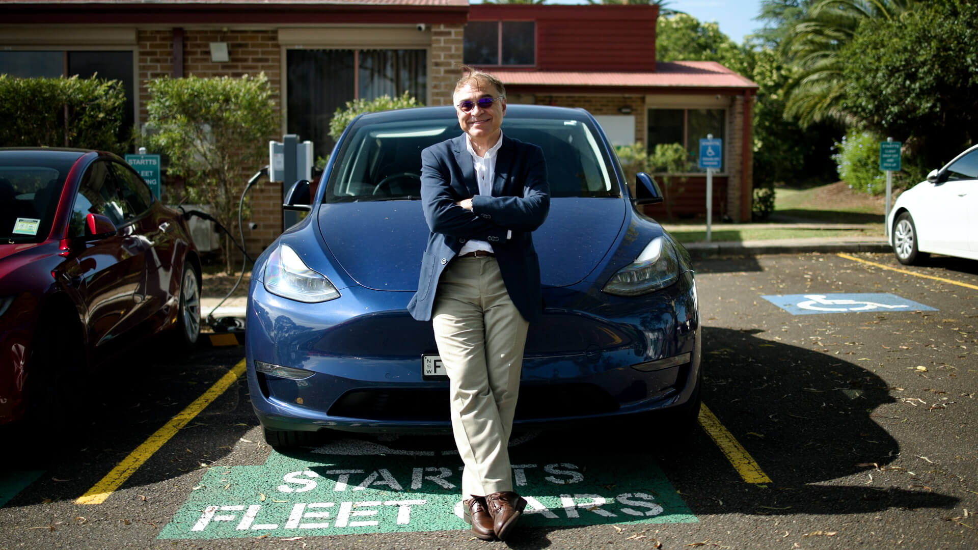 A man leaning in the hood of a blue Tesla Model Y electric vehicle