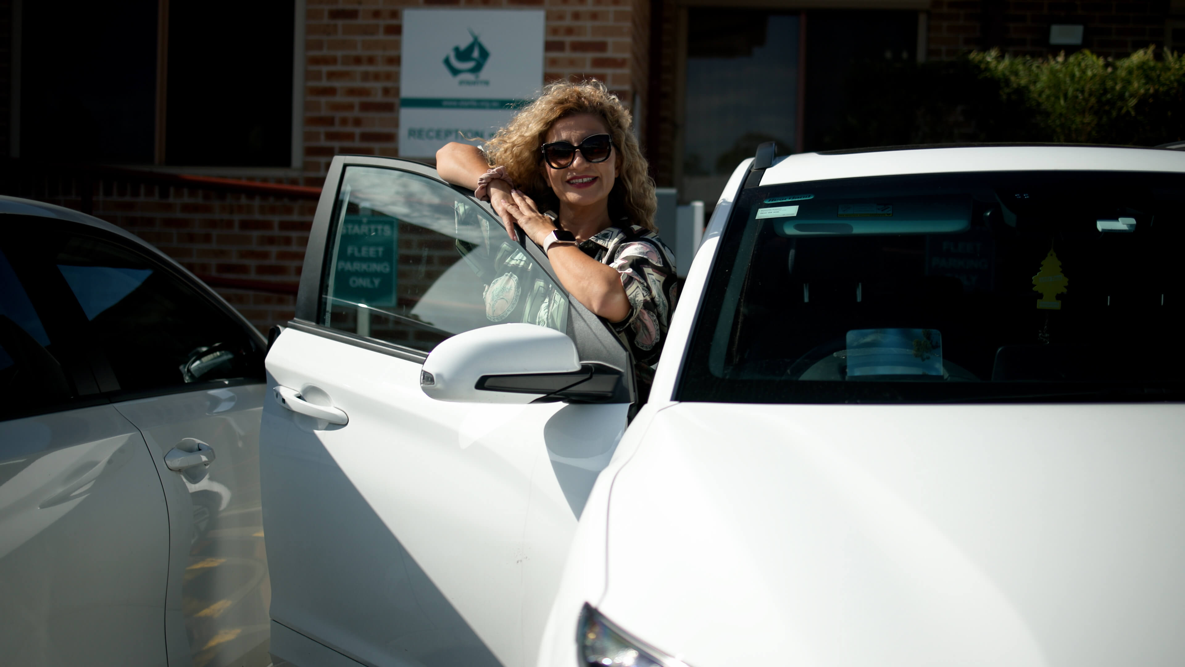 A woman standing next to a white electric vehicle