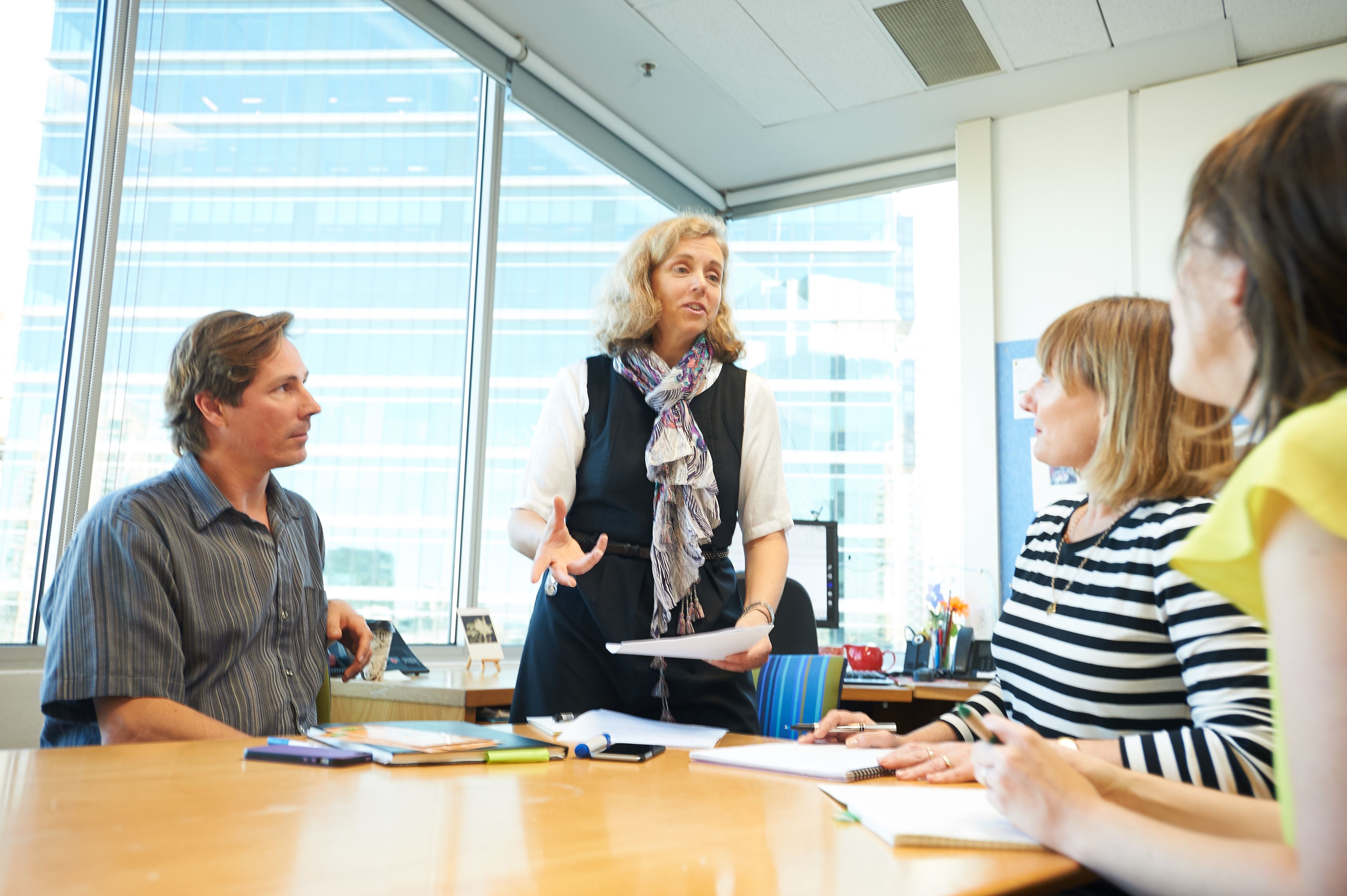 Woman stands up and talks to her team during a meeting