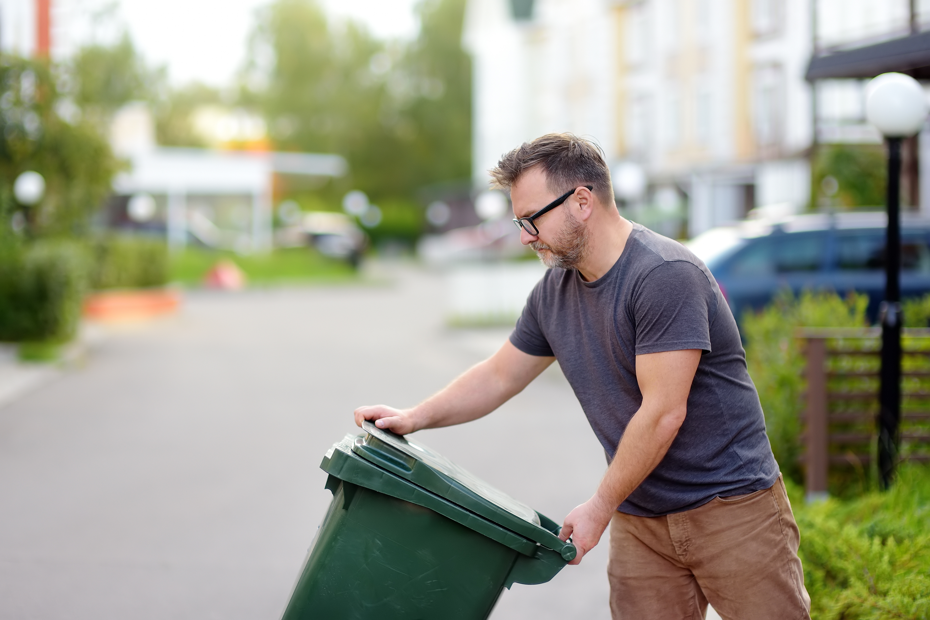A man putting his bin out on the street for pick up