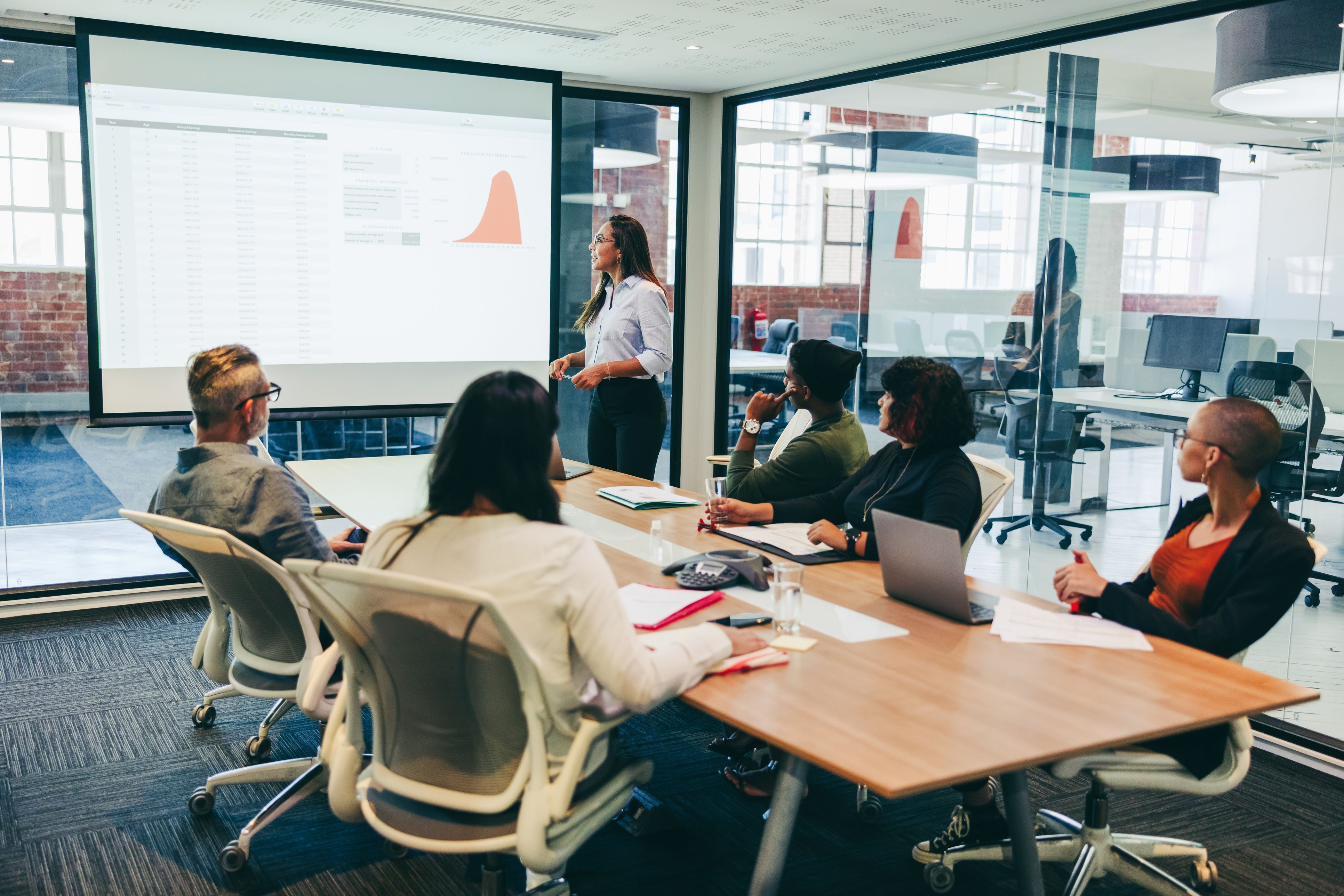 A team sitting in a meeting watching a colleague give a presentation