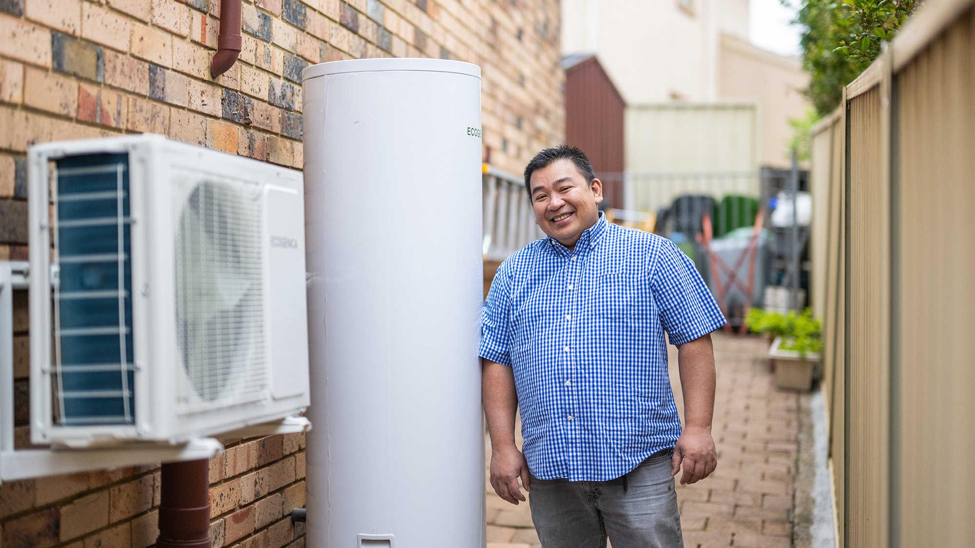 Resident standing next to his new heat pump hot water system