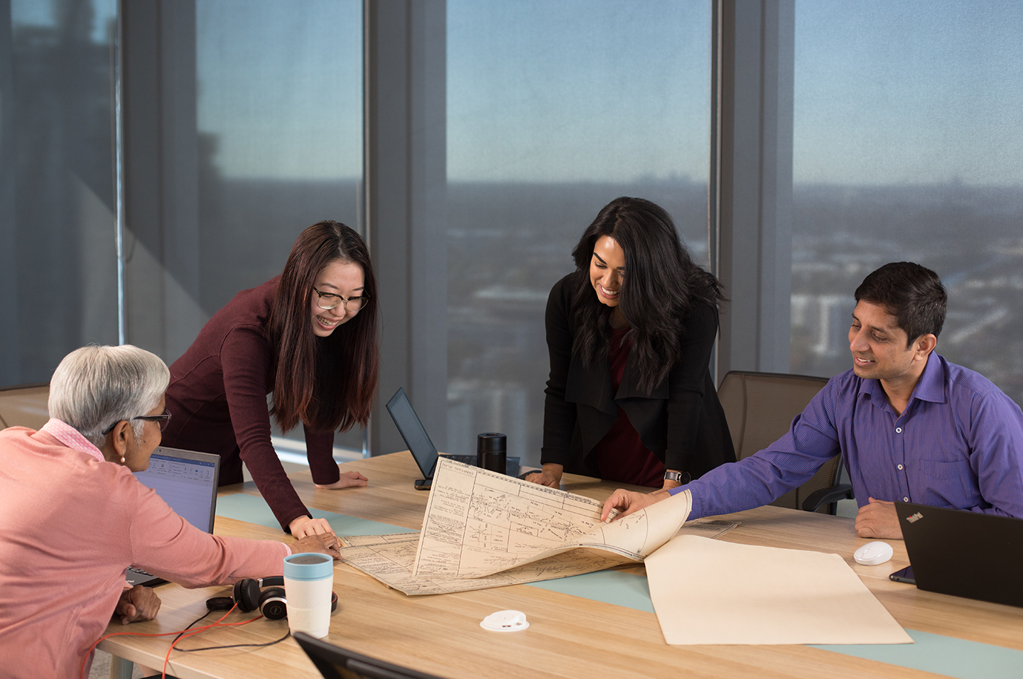 Four people in a meeting room going over plans