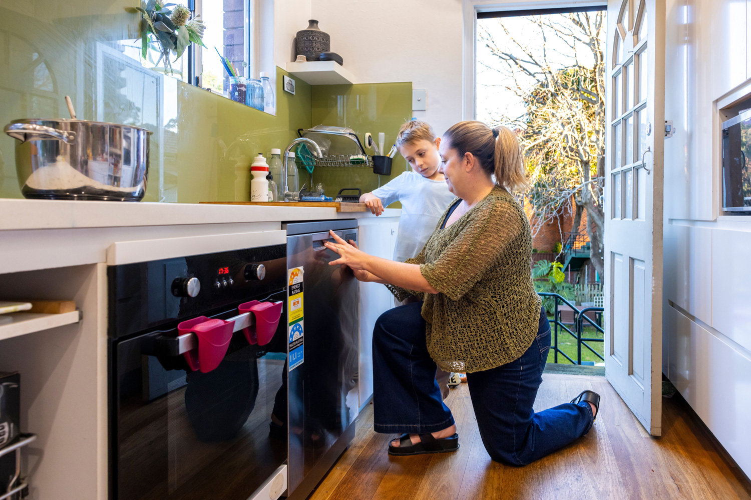 A parent and child in the kitchen loading a dishwasher