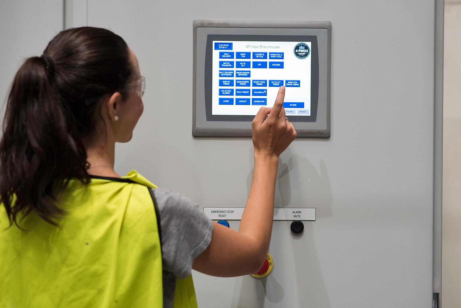 A woman in hi-vis pressing buttons on a touch screen