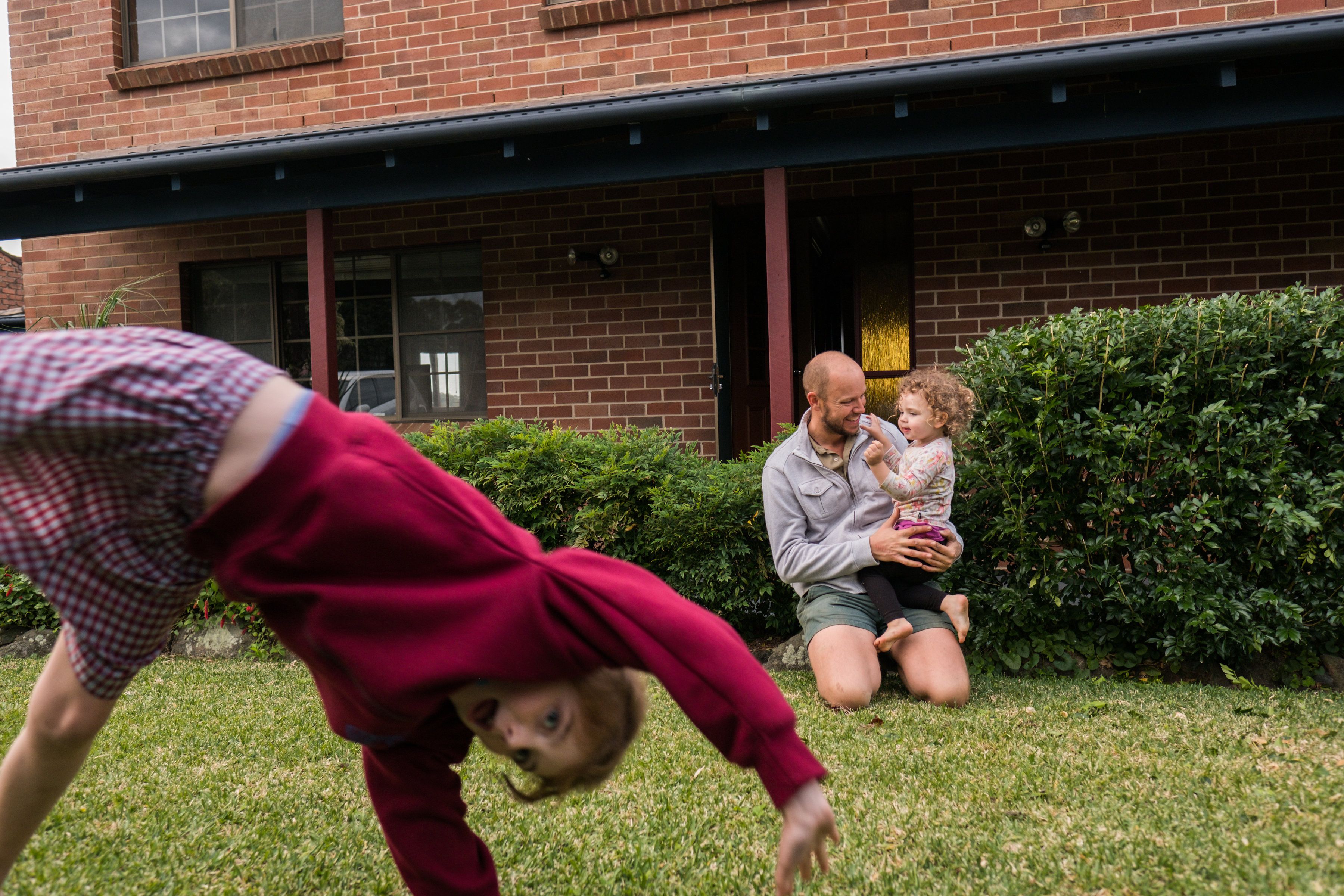 girl cartwheeling in front of dad and son