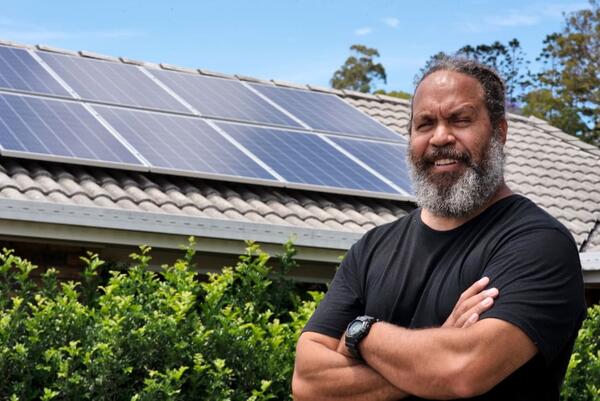 Man standing in front of roof with solar panels