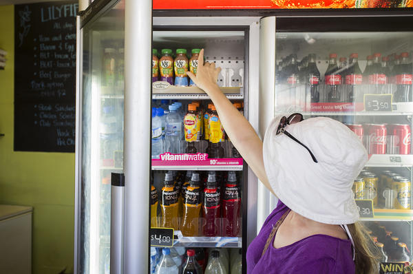 Person in takeaway shop reaches for drink in fridge