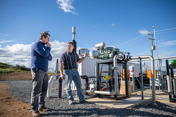 Two people standing outdoors near machinery