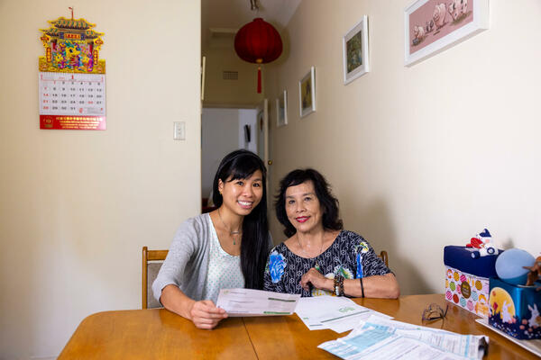 A mother and adult child reviewing electricity bills