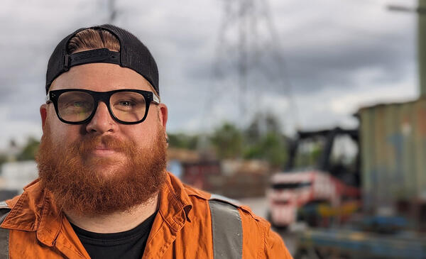 Close up of person in high visibility workwear with electricity towers in background